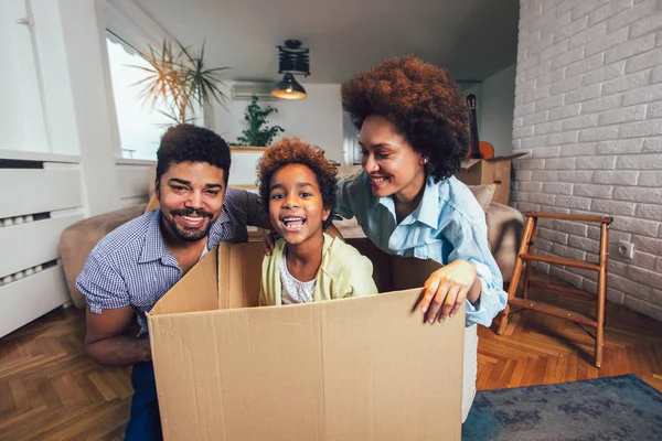Afro-amerikai család, a szülők és lánya, kicsomagolás dobozok a — Stock Fotó