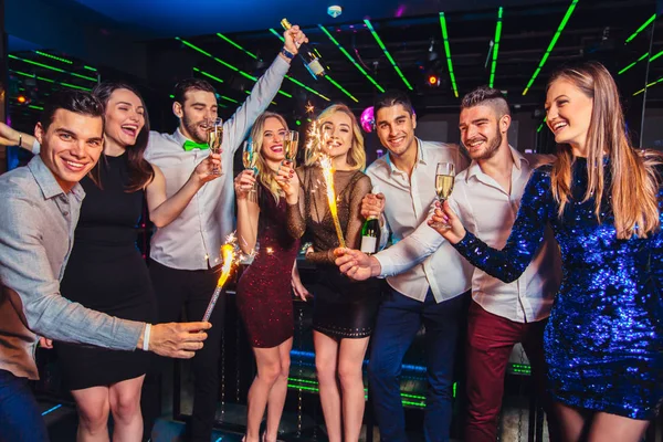 Grupo de amigos festejando em uma boate e brindando bebidas . — Fotografia de Stock