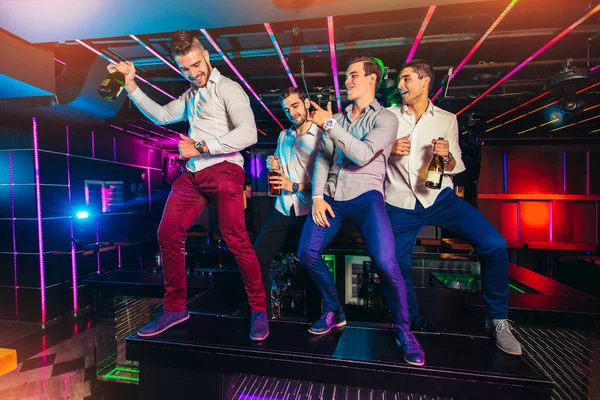 Bir grup gülümseyen erkek arkadaş gece kulübünde eğleniyor.