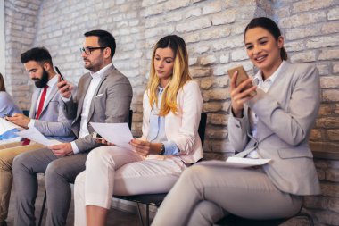 İş görüşmesi ni bekleyen iş adamları. Telefonlarını kullanıyorlar.