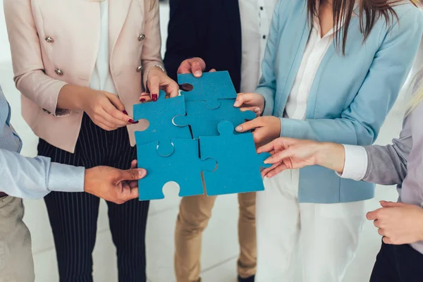 Businesspeople joining puzzle pieces in office — Stock Photo, Image