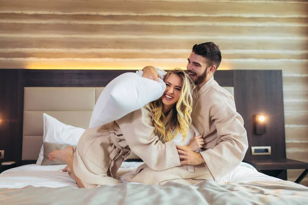 Happy Couple Having Pillow Fight in Hotel Room