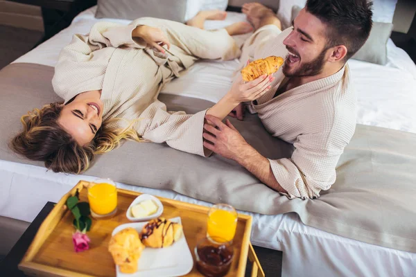 Lüks otel odasında kahvaltı eden genç mutlu çift. 