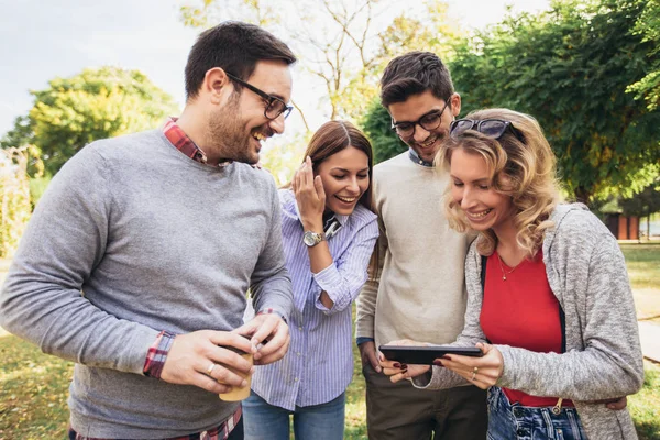 Cuatro felices jóvenes amigos sonrientes caminando al aire libre en el parque ho — Foto de Stock