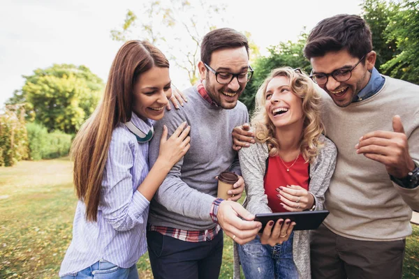 Cuatro felices jóvenes amigos sonrientes caminando al aire libre en el parque ho — Foto de Stock