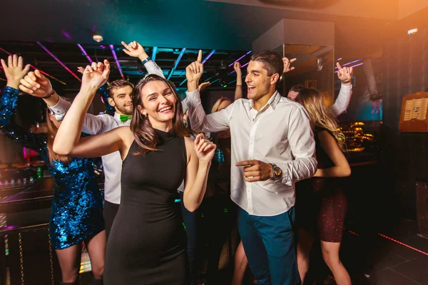 Young happy people are dancing in club. Nightlife and disco conc — Stock Photo, Image