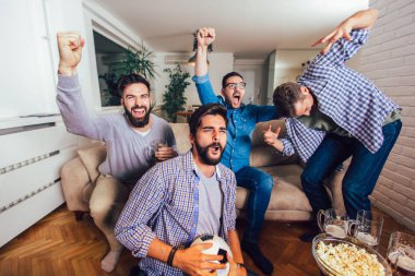 Erkekler TV 'de birlikte evde neşeli bağırarak spor izliyor. Gr