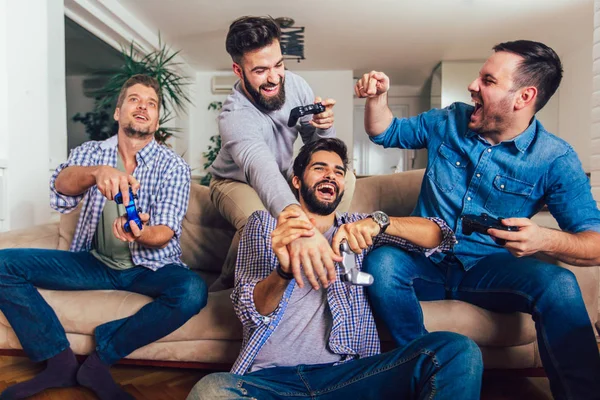 Sonriendo amigos masculinos jugando videojuegos en casa y divirtiéndose . —  Fotos de Stock