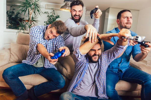 Sorrindo amigos do sexo masculino jogando videogames em casa e se divertindo . — Fotografia de Stock