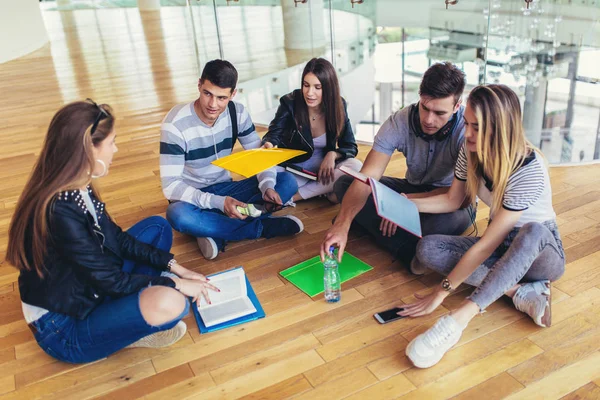 Fellow students sitting on floor in campus and preparing togethe — Stock Photo, Image