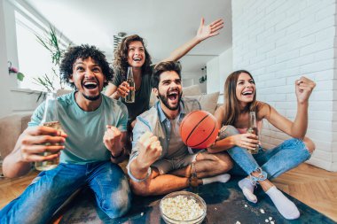 Mutlu arkadaşlar veya basketbol taraftarları televizyonda basketbol oyunu izlerken 