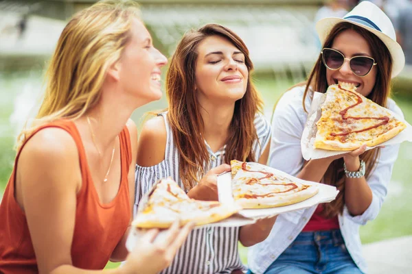 Drie mooie jonge vrouwen pizza eten na het winkelen, gelet — Stockfoto
