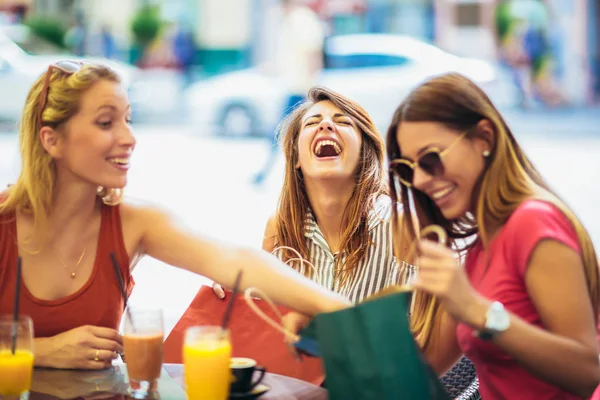 Drie jonge vrouwen in een café na een winkeltje — Stockfoto