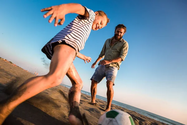 Šťastný otec a syn hrají fotbal nebo fotbal na pláži — Stock fotografie