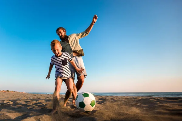 Lycklig far och son spela fotboll eller fotboll på stranden med — Stockfoto