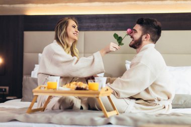 Lüks otel odasında kahvaltı eden genç mutlu çift. 