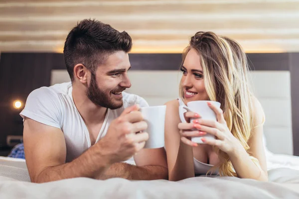 Joven pareja feliz bebiendo café en la cama por la mañana — Foto de Stock