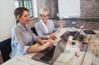 Modern ofiste dizüstü bilgisayarla çalışan iş arkadaşları.