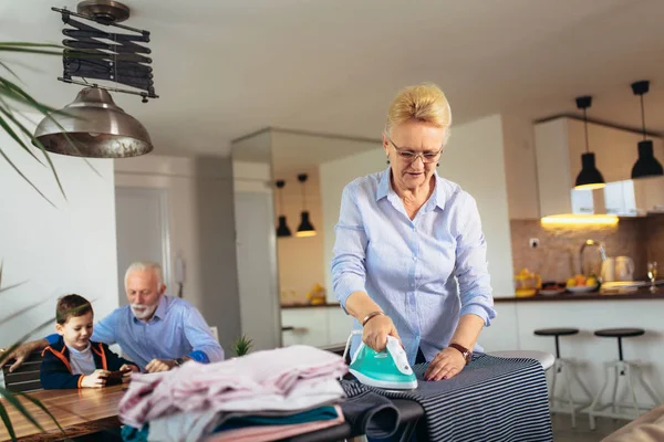 Grandma's ironing clothes, and grandfather plays with his grands — Stock Photo, Image