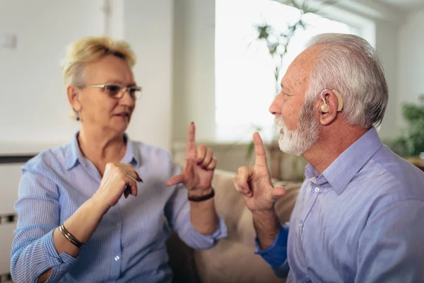 Sorridente donna anziana che parla usando il linguaggio dei segni con il suo udito — Foto Stock