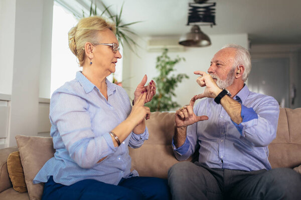 Smiling senior woman talking using sign language with her hearin