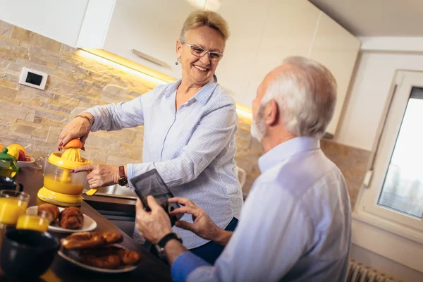 Aged couple busy look at digital tablet while having delicious b