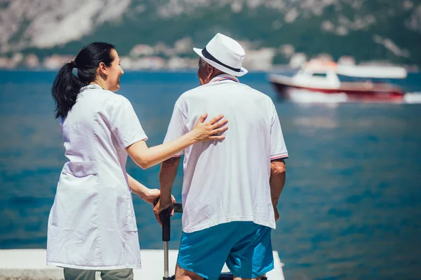 Sjuksköterska att hjälpa äldre senior man. Äldre man med en rullator med — Stockfoto