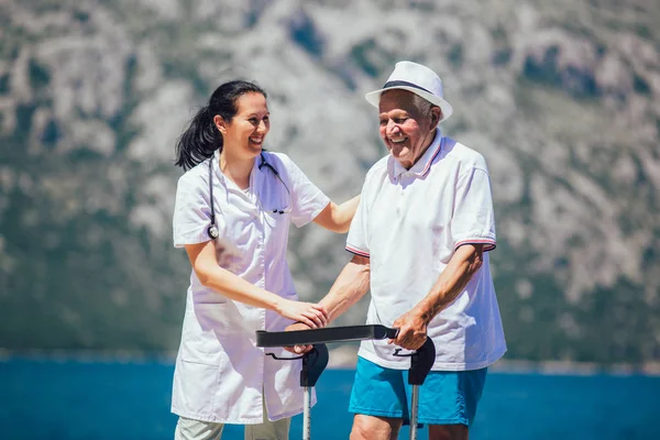 Sjuksköterska att hjälpa äldre senior man. Äldre man med en rullator med — Stockfoto
