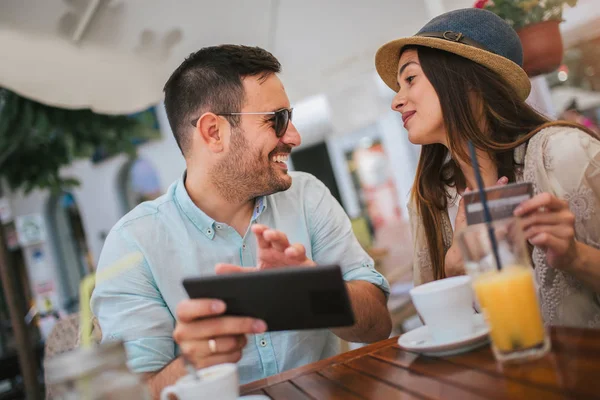 Glückliches junges Paar kauft online ein, während es in einem Café sitzt. — Stockfoto