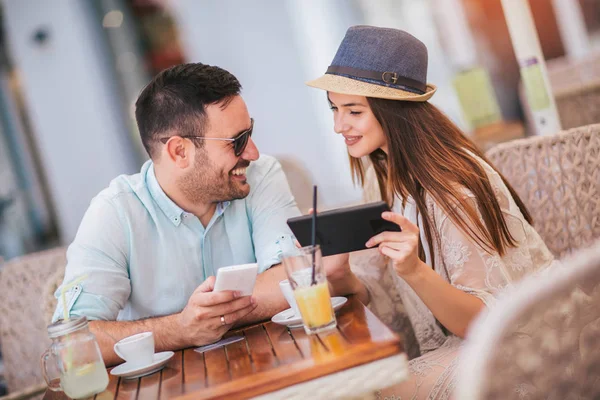 Nettes Paar schaut auf der Caféterrasse auf ein Tablet — Stockfoto