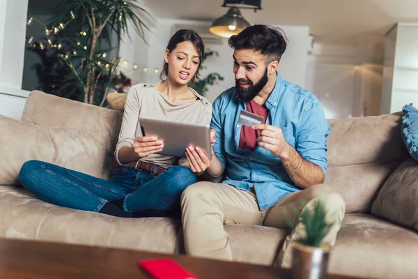 Leende par använder digitala tablett och kreditkort hemma — Stockfoto