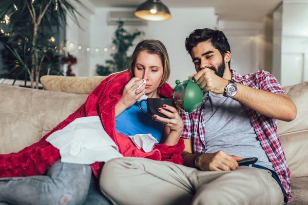 Schöner Mann, der sich um seine kranke Freundin kümmert, die auf dem Boden liegt — Stockfoto