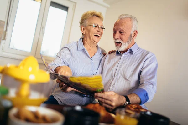 Pareja amorosa envejecida positiva leyendo periódico en casa —  Fotos de Stock