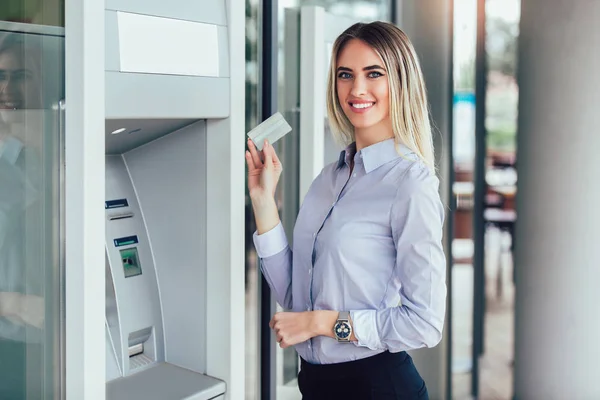 Mujer de negocios usando cajero automático. Persona que utiliza la tarjeta de crédito para retirar —  Fotos de Stock