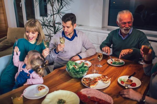 Flergenerasjonsfamilie nyter måltidet rundt bordet hjemme – stockfoto