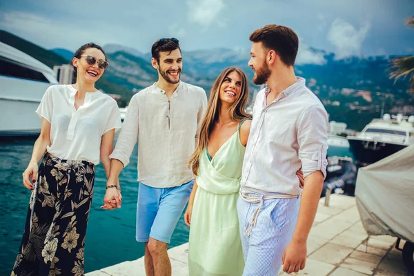Friends walking by the harbor of a touristic sea resort with boa — Stock Photo, Image