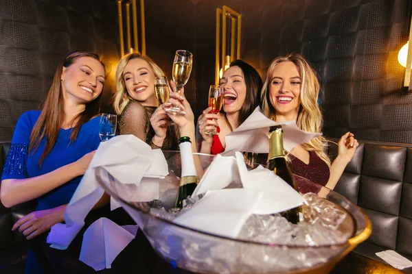 Mujeres felices tintineando copas de champán y celebrando por la noche — Foto de Stock