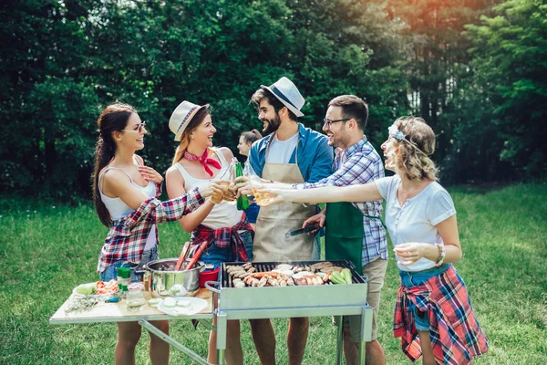 Jovens amigos se divertindo grelhando carne desfrutando de churrasqueira . — Fotografia de Stock