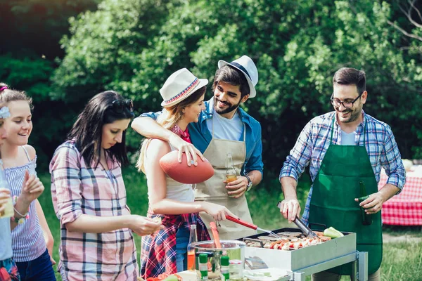 Jovens amigos se divertindo grelhando carne desfrutando de churrasqueira . — Fotografia de Stock