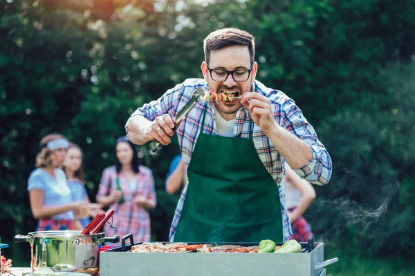 Kjekk mann som lager grillmat utendørs til venner – stockfoto