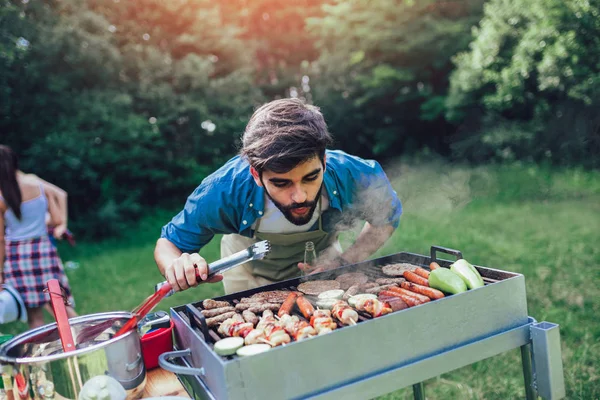 Красивий чоловік готує барбекю на відкритому повітрі для друзів — стокове фото