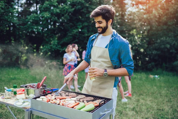 Beau mâle préparant barbecue en plein air pour les amis — Photo