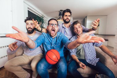 Mutlu arkadaşlar veya basketbol taraftarları televizyonda basketbol oyunu izlerken 