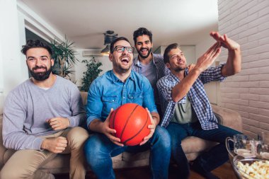 Mutlu arkadaşlar veya basketbol taraftarları televizyonda basketbol oyunu izlerken 