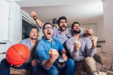 Mutlu arkadaşlar veya basketbol taraftarları televizyonda basketbol oyunu izlerken 