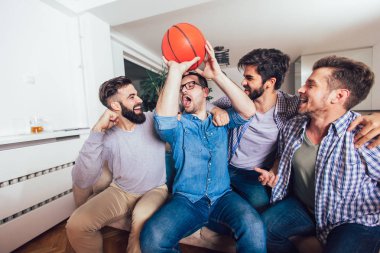 Mutlu arkadaşlar veya basketbol taraftarları televizyonda basketbol oyunu izlerken 