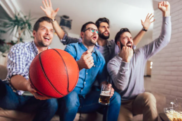 Happy friends or basketball fans watching basketball game on tv