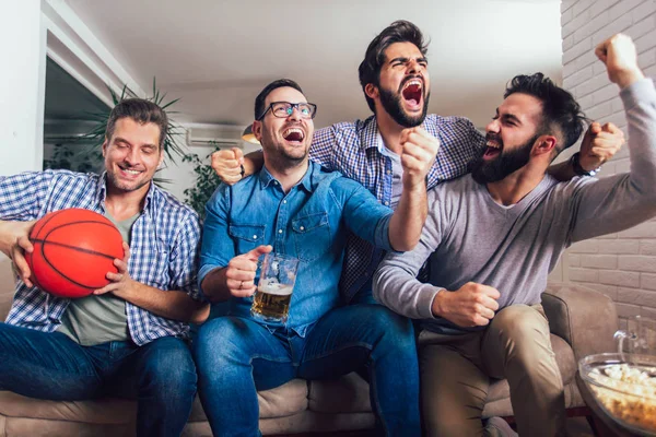 Happy friends or basketball fans watching basketball game on tv