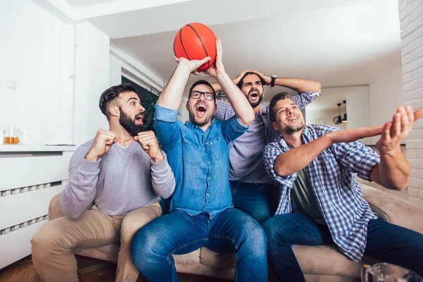 Happy friends or basketball fans watching basketball game on tv