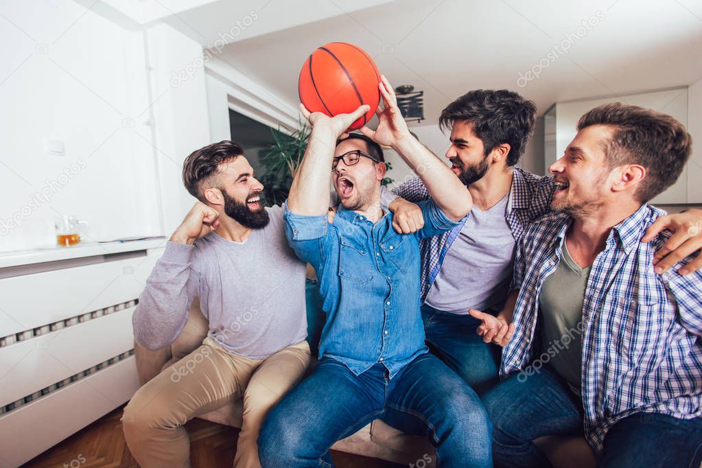 Happy friends or basketball fans watching basketball game on tv 